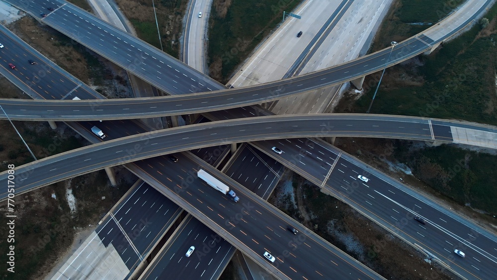 Obraz premium Cars driving along freeway go to exits from multi-level interchange. Top view from drone. Modern design of American transportation system: aerial perspective of multi-level interchange