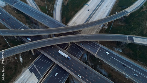 Cars driving along freeway go to exits from multi-level interchange. Top view from drone. Modern design of American transportation system: aerial perspective of multi-level interchange