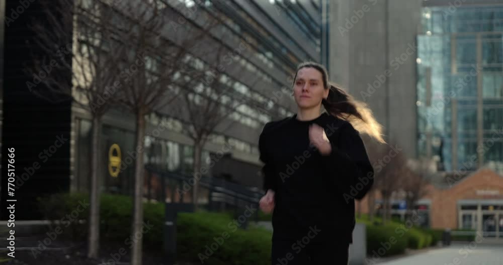 Fit woman in her 40s embraces the day with a run through quiet city streets Fit woman in her 40s embraces the day with a run through quiet city streets
