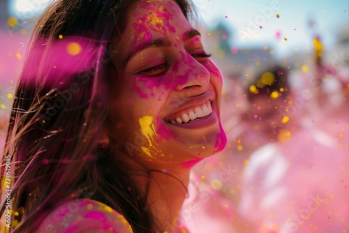 Portrait of a happy young beautiful woman celebrating Holi festival with bursts and splashes of vibrant, colorful Indian Holi powder.