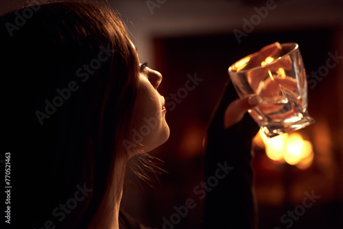 Beautiful girl with red lipstick drinks alcohol near the fireplace