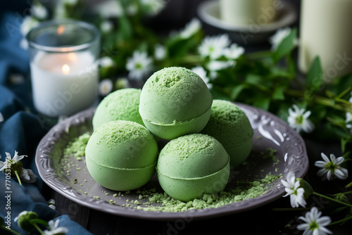 Bath bombs on the plate. Flowers and candles on the background. Cosmetics, beauty products for spa and relaxation. 