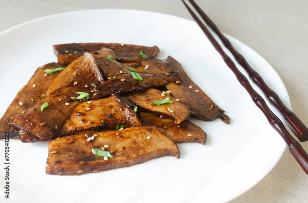 Eryngii mushroom fried with sesame and green onion on a white plate. The process of cooking Gochujang King Oyster Mushrooms. The concept of traditional Korean cuisine. Horizontal orientation. Eryngii mushroom fried with sesame and green onion on a white plate. The process of cooking Gochujang King Oyster Mushrooms. The concept of traditional Korean cuisine. Horizontal orientation.