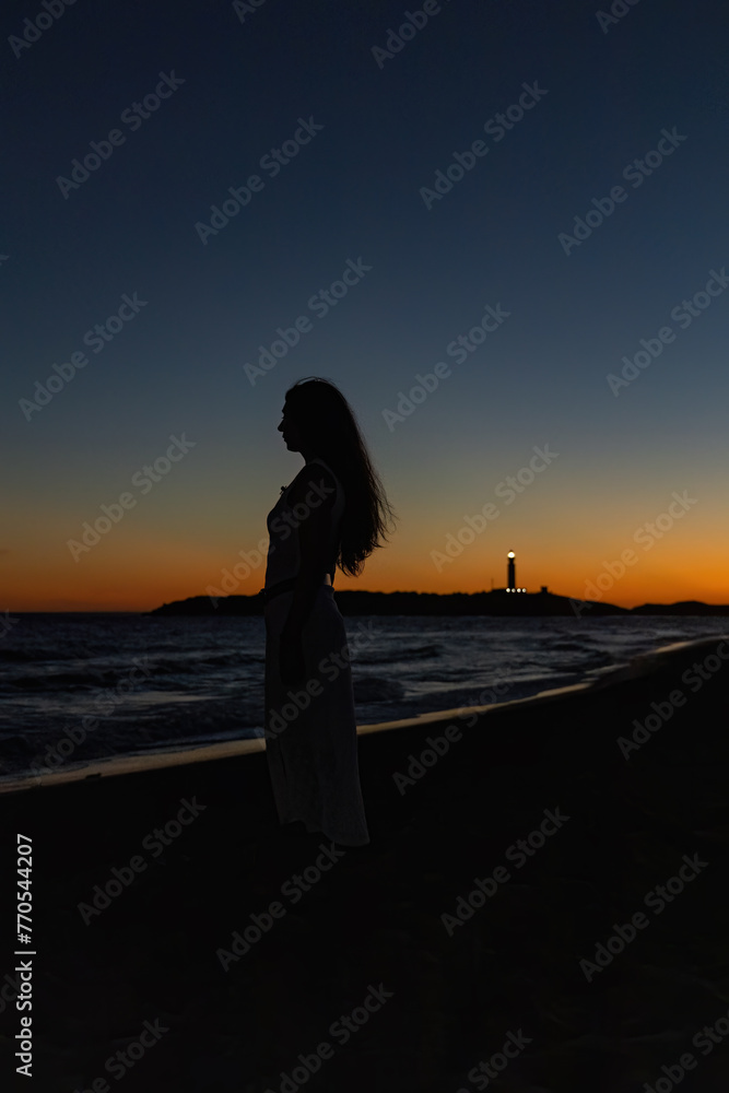 Silhouette di una ragazza al tramonto sulla spiaggia.