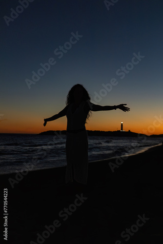Silhouette di una ragazza al tramonto sulla spiaggia.