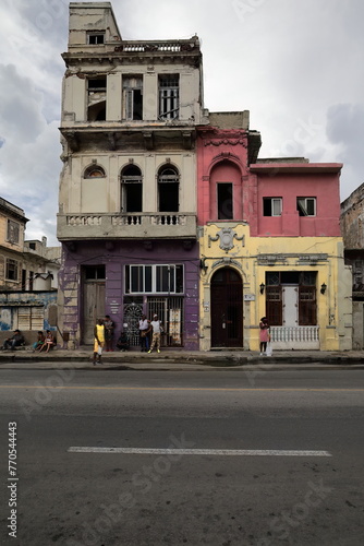 Locals at wait for shared taxis, waiting spot on Calle San Lazaro St.sidewalk under colorist facades of stepped, dilapidated houses. Havana-Cuba-115