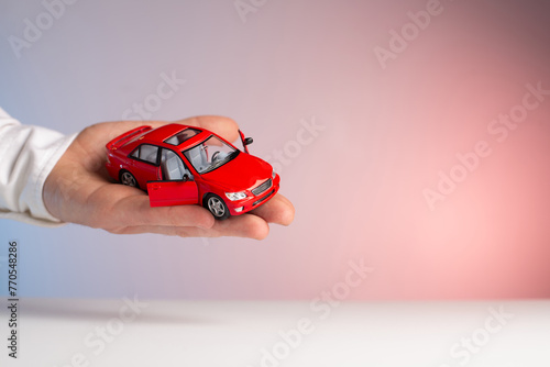 Red toy car in man hand. Sale car