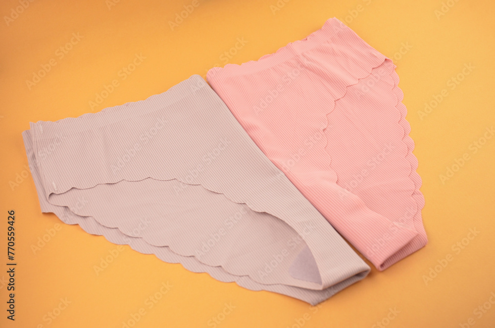 Peach pink and lilac (lavender, purple) seamless (invisible) women's underwear (lingerie, panties, briefs) with wavy edge isolated, side front view, closeup Peach pink and lilac (lavender, purple) seamless (invisible) women's underwear (lingerie, panties, briefs) with wavy edge isolated, side front view, closeup