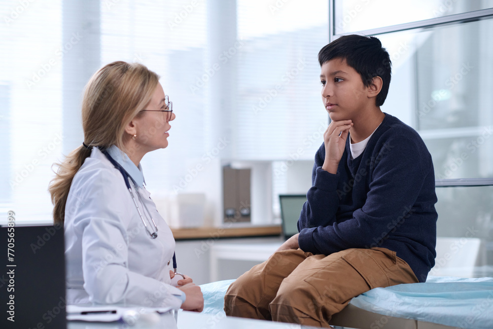 Side view portrait of young Middle Eastern boy talking to female doctor in pediatric clinic Side view portrait of young Middle Eastern boy talking to female doctor in pediatric clinic
