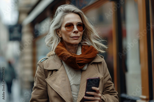 Business middle-aged woman engaging with her smartphone while walking down the street. Digital connectivity amidst the hustle and bustle of urban surroundings. Modern-day life concept