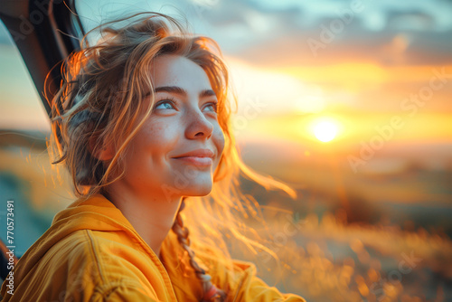 Happy Blonde Traveler Woman Leaning Out of Car Window Breathing fresh air and Watching Sunset while Daydreaming Imagining her Future © Eduard Borja