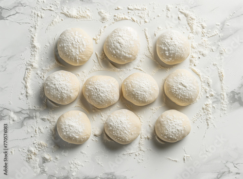 Top view of dough balls dusted with flour on a table