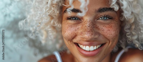 close-up of a smiling mixed race woman with beautiful eyes and smile. white curly hair and freckles on her cheeks. photo