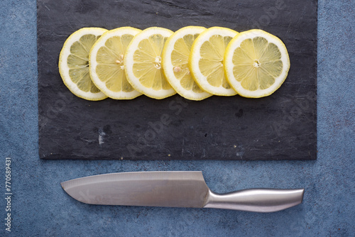 Lemon slices on a slate plate and kitchen knife © WINDCOLORS