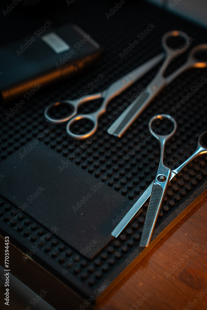 Scissor and clipper in barbeshop on dark rubber background Scissor and clipper in barbeshop on dark rubber background