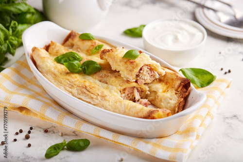 Crepes rolls stuffed with chicken meat, ham and cheese, baked with bechamel sauce and cheese. 