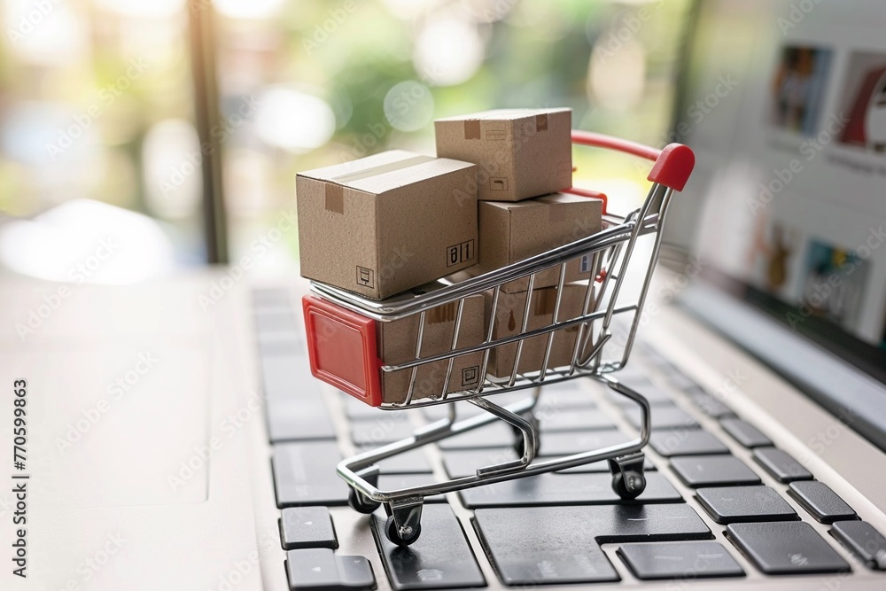 A miniature shopping cart filled with boxes placed on a laptop keyboard A miniature shopping cart filled with boxes placed on a laptop keyboard