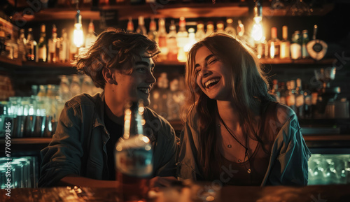 A man and a woman are sitting at a bar, smiling and laughing. The bar is filled with various bottles and glasses, and there is a bottle of beer on the table.