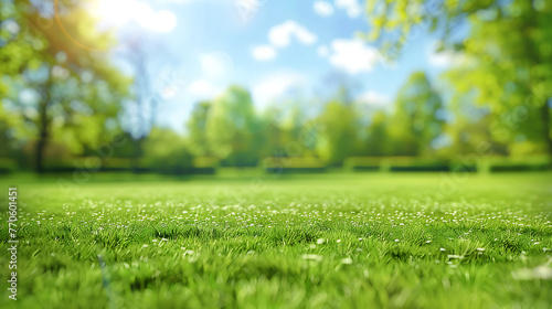 Beautiful blurred background image of spring nature with a neatly trimmed lawn surrounded by trees against a blue sky with clouds on a bright sunny