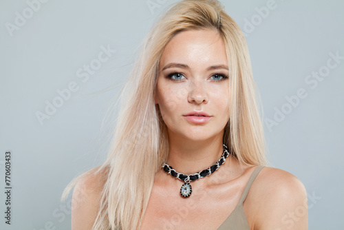 Celebrity fashion female model with long blonde hairstyle and shiny fresh skin on white background, studio portrait