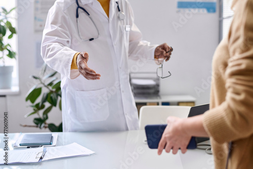 Close up of unrecognizable doctor greeting patient in medical clinic and gesturing for seat copy space