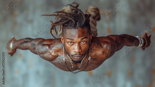  A man in dreadlocks does a handstand before a wall
