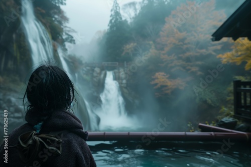 overtheshoulder view of person looking at waterfall from onsen