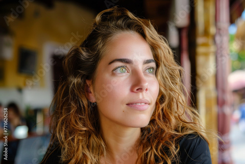 Portrait of a young beautiful woman with curly hair in a cafe 