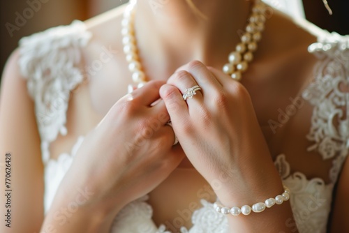 closeup of bride clasping pearl necklace around her neck photo