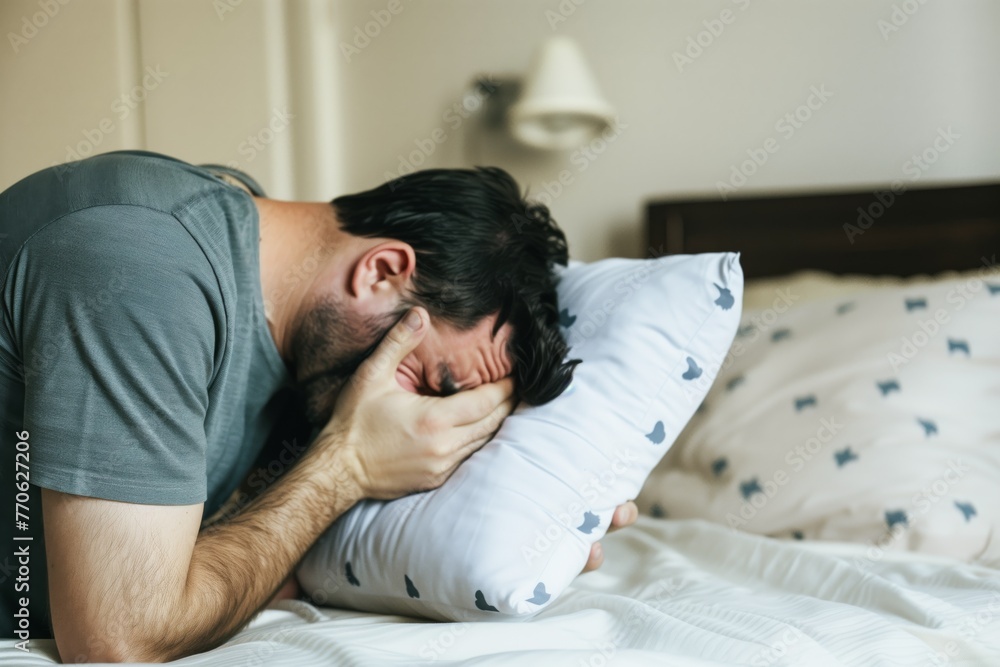 man sobbing into a pillow on his bed man sobbing into a pillow on his bed