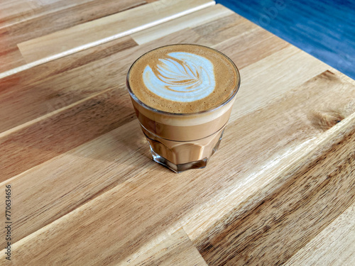 A glass of coffee latte on wooden texture of the table