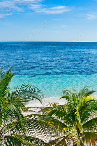 ISLA MUJERES ISLAND, MEXICO - DECEMBER 2021: The white sand beach with umbrellas, bungalow bar, boats, birds, and cocos palms, turquoise caribbean sea, Isla Mujeres island, Caribbean Sea, Cancun. 