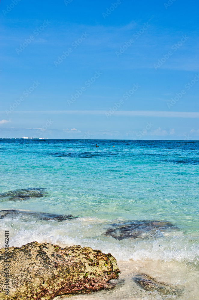ISLA MUJERES ISLAND, MEXICO - DECEMBER 2021: The white sand beach with umbrellas, bungalow bar, boats, birds, and cocos palms, turquoise caribbean sea, Isla Mujeres island, Caribbean Sea, Cancun. 
