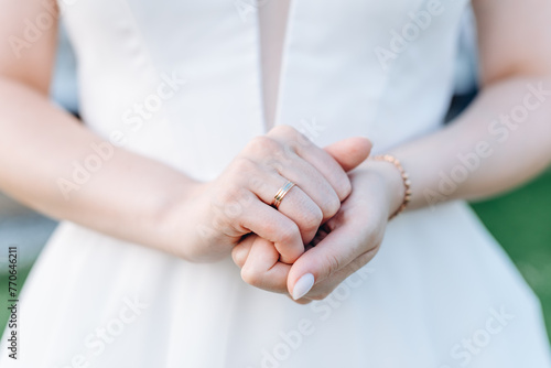 bride holds hands together with wedding ring
