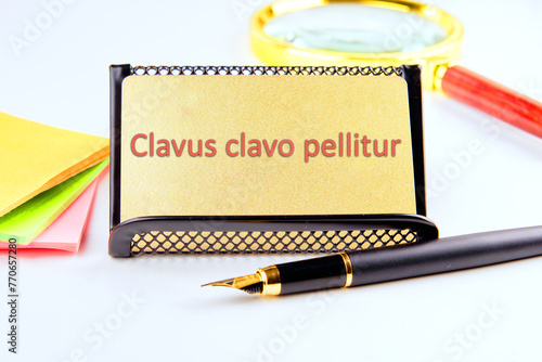 Clavus clavo pellitur. The ancient Greek expression translates as, A wedge is knocked out with a wedge. on a gold business card with highlighted text photo