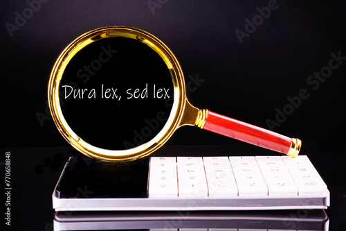 Dura Lex Sed Lex. A Latin phrase meaning The law is harsh, but it is (still) the law. through a magnifying glass on a black background in white font photo