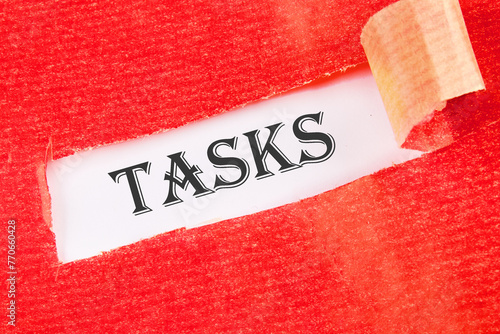 Business concept. TASKS - word on a white background under torn paper