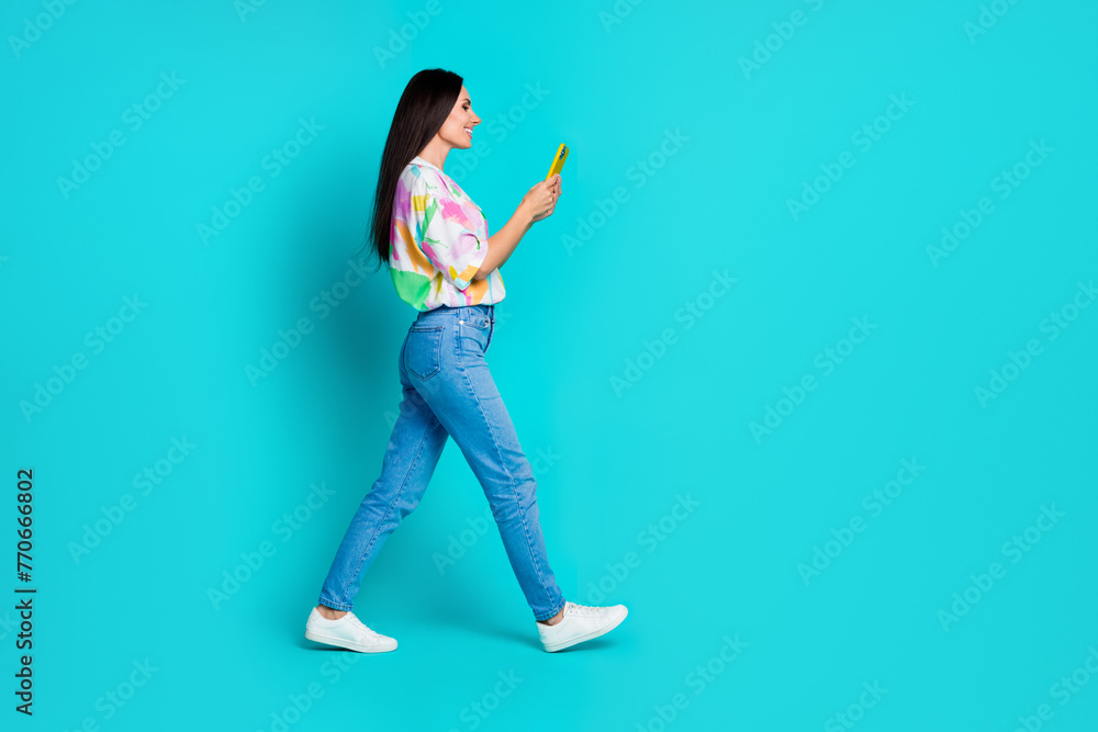 Photo of cheerful lovely woman blogger wear trendy print clothes chatting writing reading isolated on cyan color background Photo of cheerful lovely woman blogger wear trendy print clothes chatting writing reading isolated on cyan color background