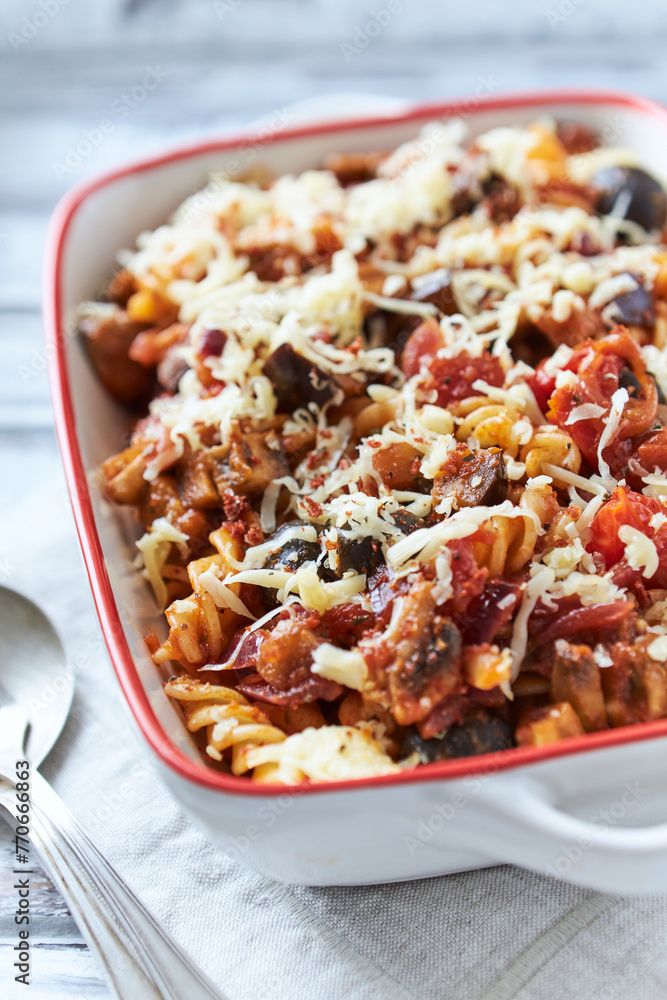 Baked fusilli pasta with cherry tomatoes, olives and mozzarella cheese. Bright wooden background. Close up. Baked fusilli pasta with cherry tomatoes, olives and mozzarella cheese. Bright wooden background. Close up.