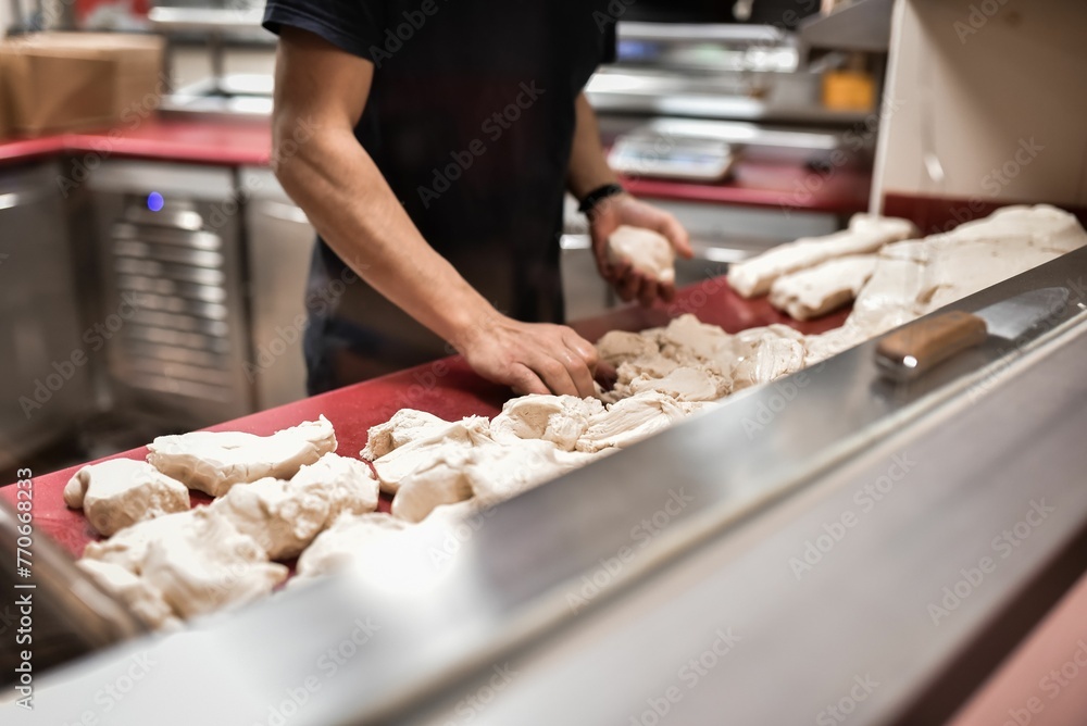 an image of a man rolling up donuts on a conveyer belt an image of a man rolling up donuts on a conveyer belt