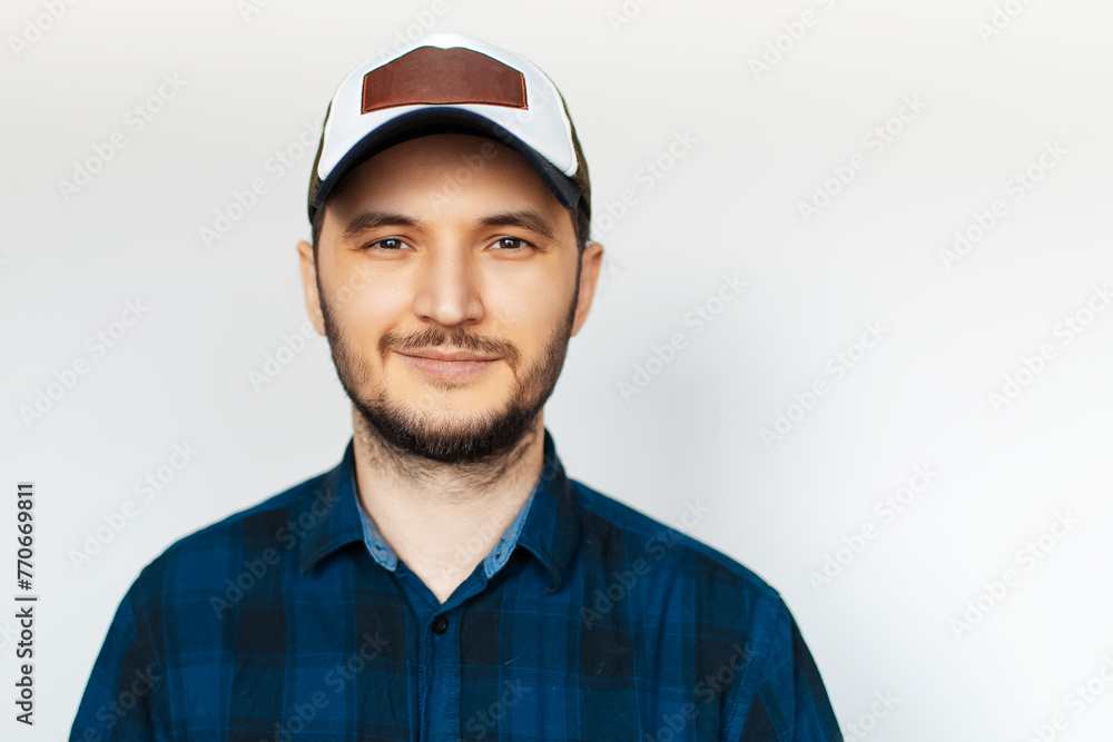 Studio portrait of young man in blue shirt wearing cap, on white background. Studio portrait of young man in blue shirt wearing cap, on white background.