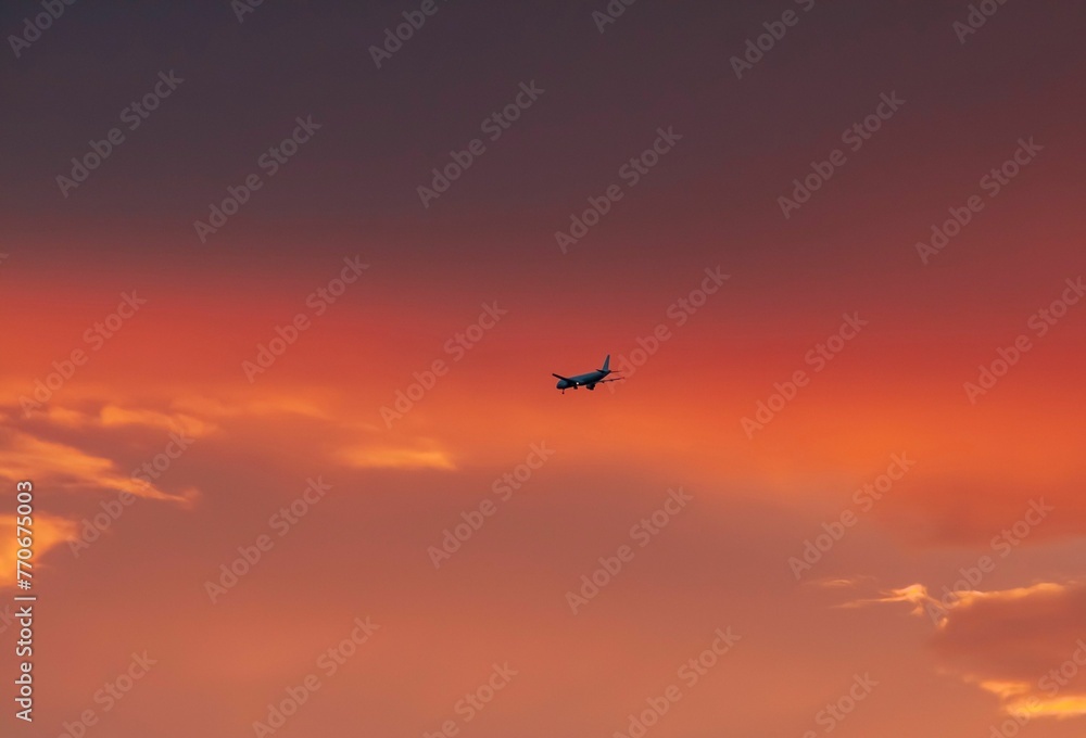 Scenic view of an airplane flying in the sky at pink sunset