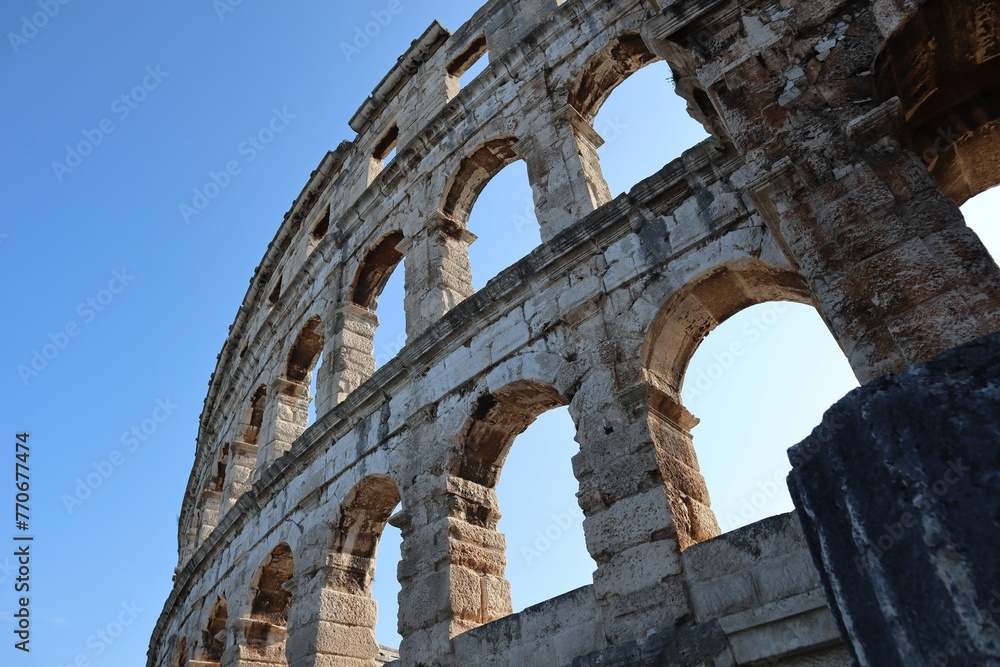 Low angle shot of the Pula Arena amphitheater in broad daylight under blue sky