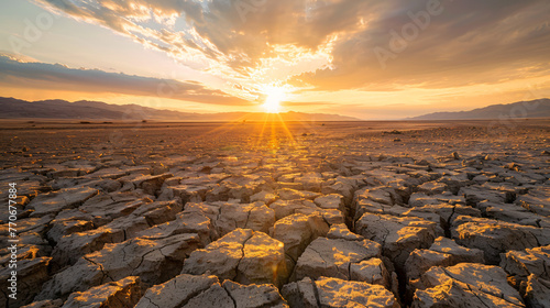 Heatwaves visible over a dry cracked earth landscape with a mirage effect shimmering in the distance illustrating extreme temperatures. photo