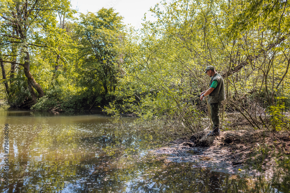 Recreational fisherman at river bank trying to catch a fish. Angler lifestyle concept.