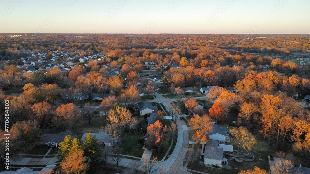 an aerial view of a neighborhood at sunrise, including the road