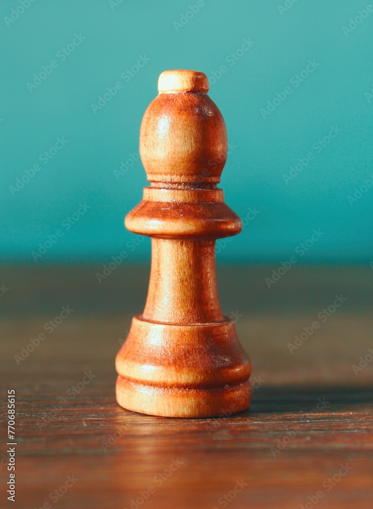 Close-up of a wooden chess pawn on a blue background is in focus Close-up of a wooden chess pawn on a blue background is in focus