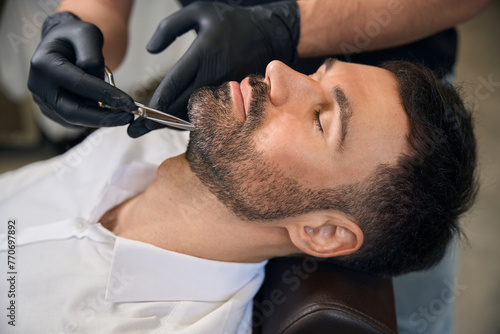 Beard styling and cut with scissors for man at barbershop