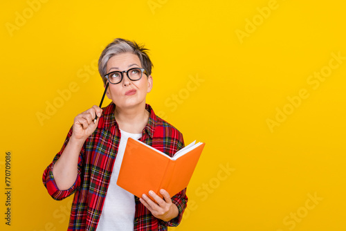 Photo of pensive person hold pencil notepad look empty space brainstorm ponder isolated on yellow color background