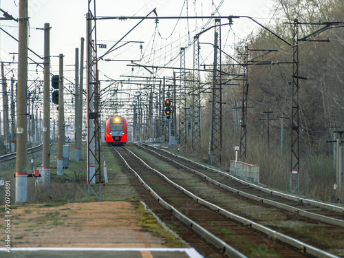 Electric transport on the railway. Contact power lines for commuter trains. A modern urban electric train on the railway tracks. Transportation of passengers within the city limits.